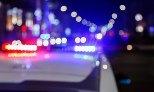 defocused photo of police car lights at night in city with selective focus and blurry car traffic in the bokeh