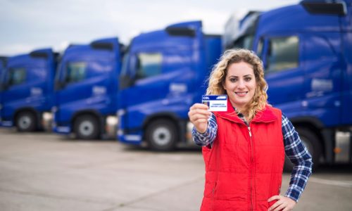Woman,Truck,Driver,Proudly,Holding,Commercial,Driving,License.,In,Background
